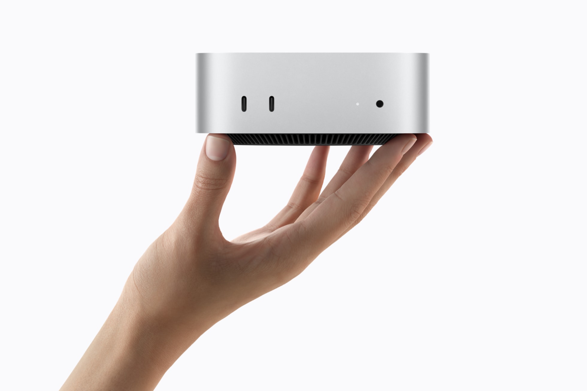 En hånd holder den kompakte Mac mini og viser frontportene