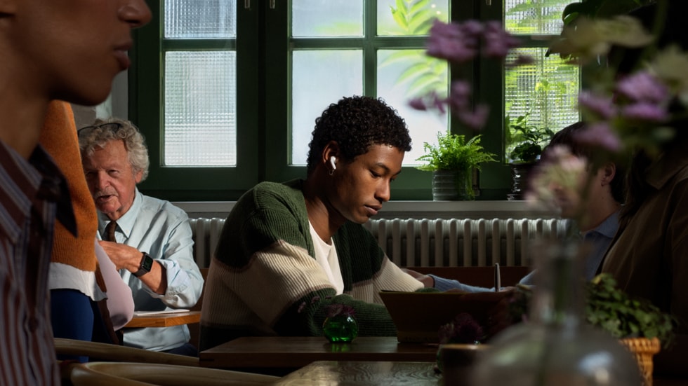 Person bruker AirPods 5 på en travel restaurant