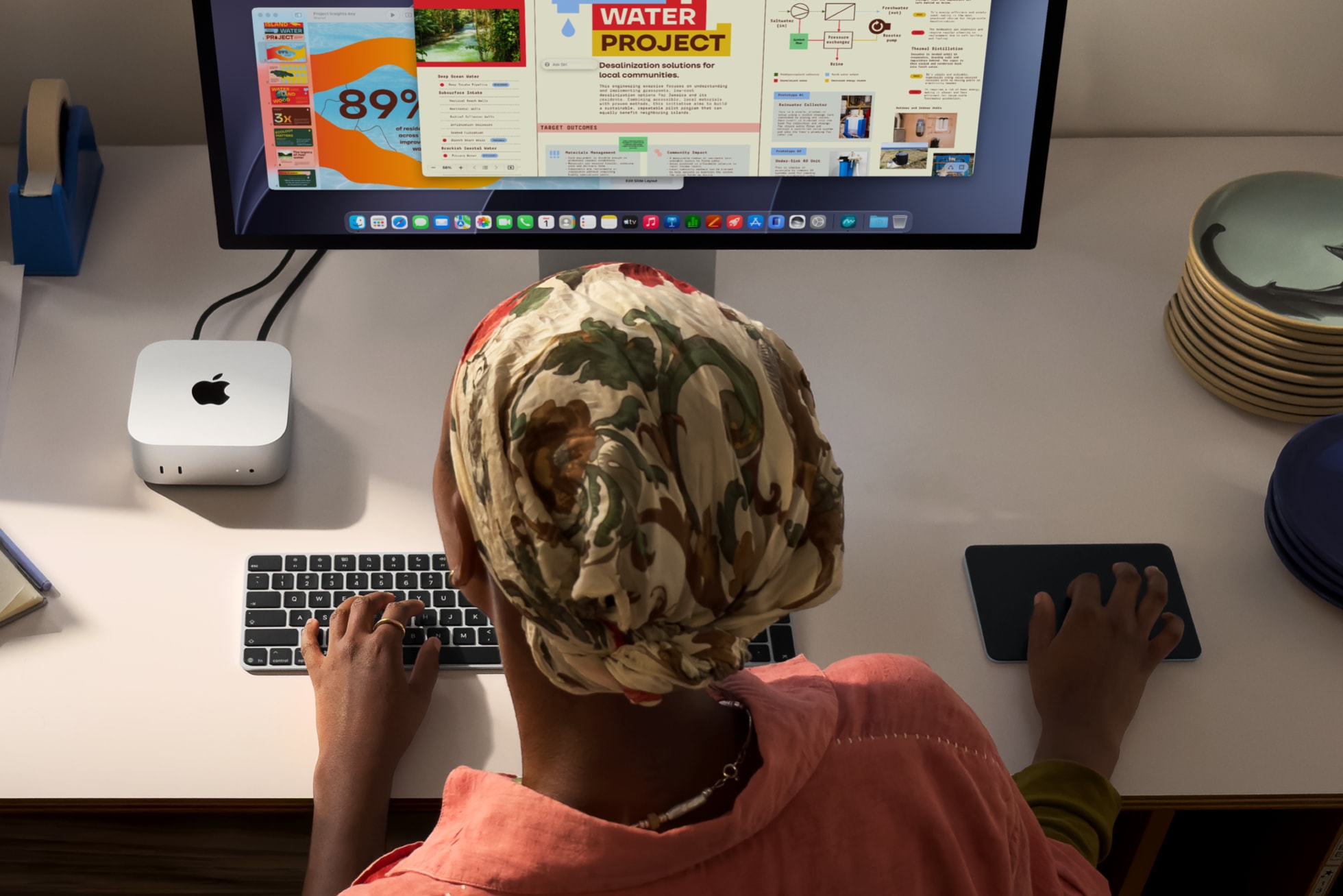 En person arbeider ved et skrivebord med Mac mini og ekstern skjerm